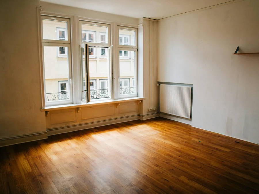 Leerer Altbauraum mit Dielenboden und Kastenfenster nach der Räumung